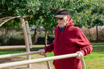 Lateral view of an old man using parallel bars in a park