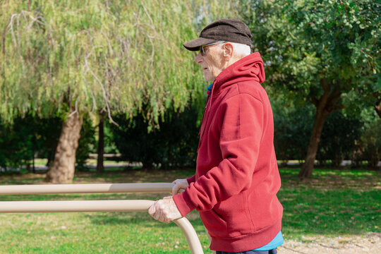 Half body lateral view of an old man using parallel bars in a park