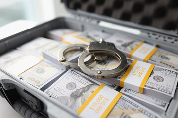 Handcuffs on pile of cash in suitcase