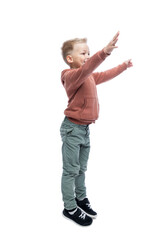 The joyful boy raised his hands up. A blond guy in a brown hoodie and gray trousers. Positivity and happiness. Isolated on white background. Vertical.