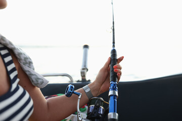 Female sitting in boat and holding fish rod in hands