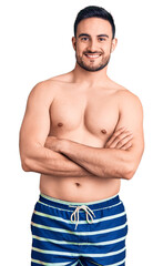 Fototapeta premium Young handsome man wearing swimwear happy face smiling with crossed arms looking at the camera. positive person.