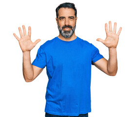 Middle aged man with beard wearing casual blue t shirt showing and pointing up with fingers number ten while smiling confident and happy.