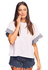 Young hispanic woman wearing casual clothes touching mouth with hand with painful expression because of toothache or dental illness on teeth. dentist