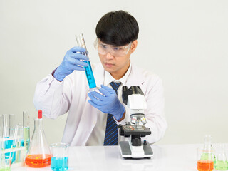 Asian male student scientist Wearing a doctor's gown in the lab looking at the chemist. caused by...