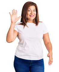 Middle age latin woman wearing casual white tshirt showing and pointing up with fingers number five while smiling confident and happy.