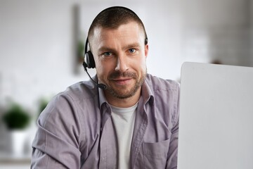 Smiling man working with headset in modern office.