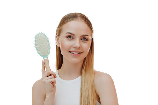 beautiful young woman holds a comb in her hands. Blonde woman with long straight hair on a gray background