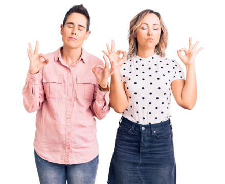 Couple of women wearing casual clothes relax and smiling with eyes closed doing meditation gesture with fingers. yoga concept.