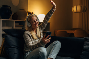 Cheerful Caucasian woman is listening to music at home