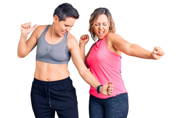 Couple of women wearing sportswear dancing happy and cheerful, smiling moving casual and confident listening to music