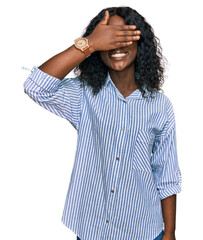 Beautiful african young woman wearing casual clothes and glasses smiling and laughing with hand on face covering eyes for surprise. blind concept.