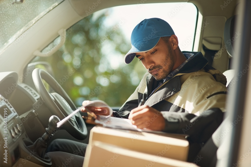 Canvas Prints Updating his delivery status. Shot of a delivery man reading addresses while sitting in a delivery van.