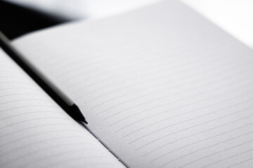 Black pencil put on the blank white paper notebook (diary) between two sheet page. Book with line...