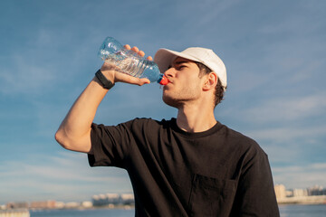 A man drinking clean water from a bottle during a break between workouts.