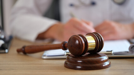 Wooden judge gavel on table doctor doing paperwork on blurred background