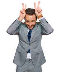Middle age man wearing business clothes posing funny and crazy with fingers on head as bunny ears, smiling cheerful