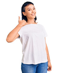 Young woman wearing casual clothes smiling doing phone gesture with hand and fingers like talking on the telephone. communicating concepts.