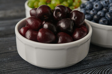 ripe cherries in white bowls on the table