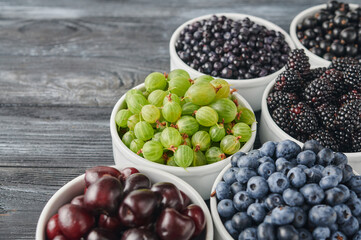 bowls with wild berries, wooden table background