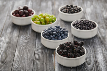 bowls with berries, a mix of fresh berries on a wooden table