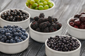 Fototapeta na wymiar bowls with wild berries, wooden table background