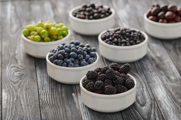 Fototapeta na wymiar Fresh berries in six bowls on a wooden background. Fruit berry background.