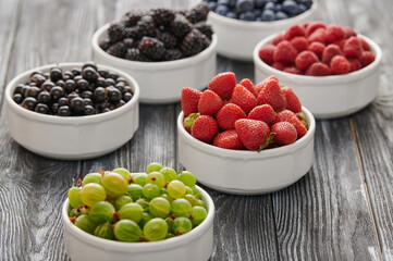 Fresh berries in six bowls on a wooden background. Fruit berry background.
