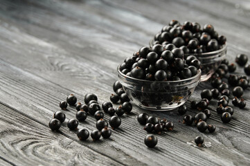 ripe black currants in bowls on a wooden table