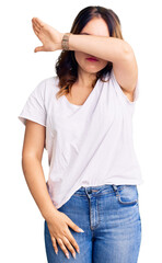 Young beautiful caucasian woman wearing casual white tshirt covering eyes with arm, looking serious and sad. sightless, hiding and rejection concept