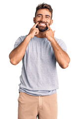 Young hispanic man wearing casual clothes smiling with open mouth, fingers pointing and forcing...