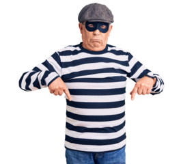 Senior handsome man wearing burglar mask and t-shirt pointing down looking sad and upset, indicating direction with fingers, unhappy and depressed.