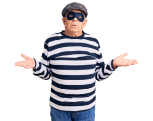 Senior handsome man wearing burglar mask and t-shirt clueless and confused with open arms, no idea concept.