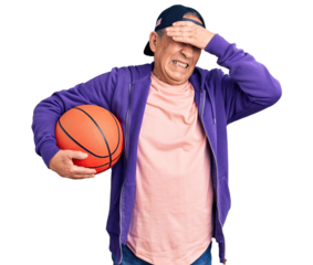 Senior handsome grey-haired man holding basketball ball stressed and frustrated with hand on head, surprised and angry face