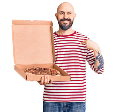 Young handsome man holding delivery pizza box pointing finger to one self smiling happy and proud