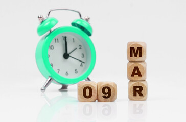 On a white background, a green alarm clock and a calendar with the inscription - March 9