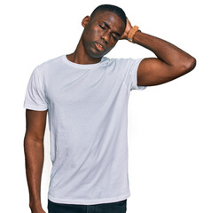 Young african american man wearing casual white t shirt confuse and wondering about question....