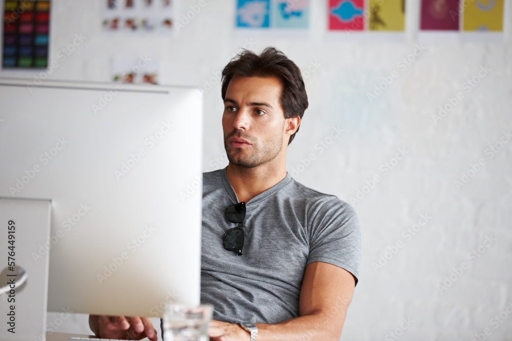 Poster doing work online. a handsome young man sitting in front of his computer.