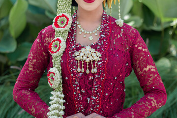 Indonesian wedding accessories. A female model who wears make-up and a traditional wedding dress or attire. Portrait of a traditional Javanese bride. Indonesian bride. Red wedding dress.