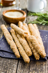 Italian grissini bread sticks with sesame seeds on wooden kitchen table.