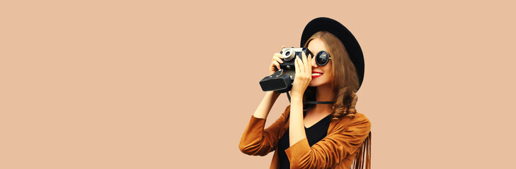 Portrait of happy smiling young woman photographer with film camera on brown background