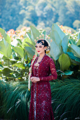 Fototapeta na wymiar Indonesian wedding accessories. A female model who wears make-up and a traditional wedding dress or attire. Portrait of a traditional Javanese bride. Indonesian bride. Red wedding dress.