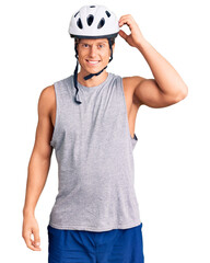 Young handsome man wearing bike helmet confuse and wonder about question. uncertain with doubt, thinking with hand on head. pensive concept.