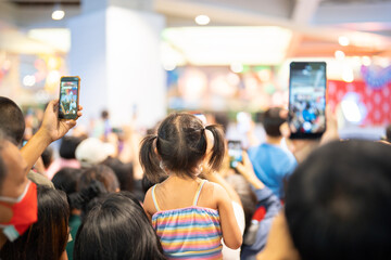 Crowd, group of young people kid, cheering in live music concert in front of colorful stage lights...