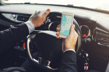 Naklejka premium Getting around with the help of technology. Closeup shot of an unrecognizable businessman using his cellphone while driving.