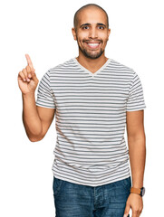 Fototapeta premium Hispanic adult man wearing casual clothes showing and pointing up with finger number one while smiling confident and happy.