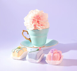 A Springtime Tea Celebration: A Pastel Green Teacup with Gold Handle, a Pink Flower, and an Assortment of Pastel Cake Delights