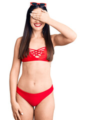 Young beautiful caucasian woman wearing bikini smiling and laughing with hand on face covering eyes for surprise. blind concept.