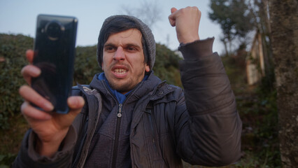 Man in Natural Green Scenery Uses Phone and Reacts with Joy to App Concept