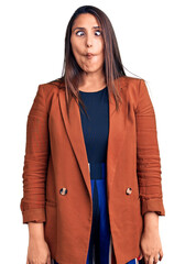 Young beautiful brunette woman wearing elegant clothes making fish face with lips, crazy and...